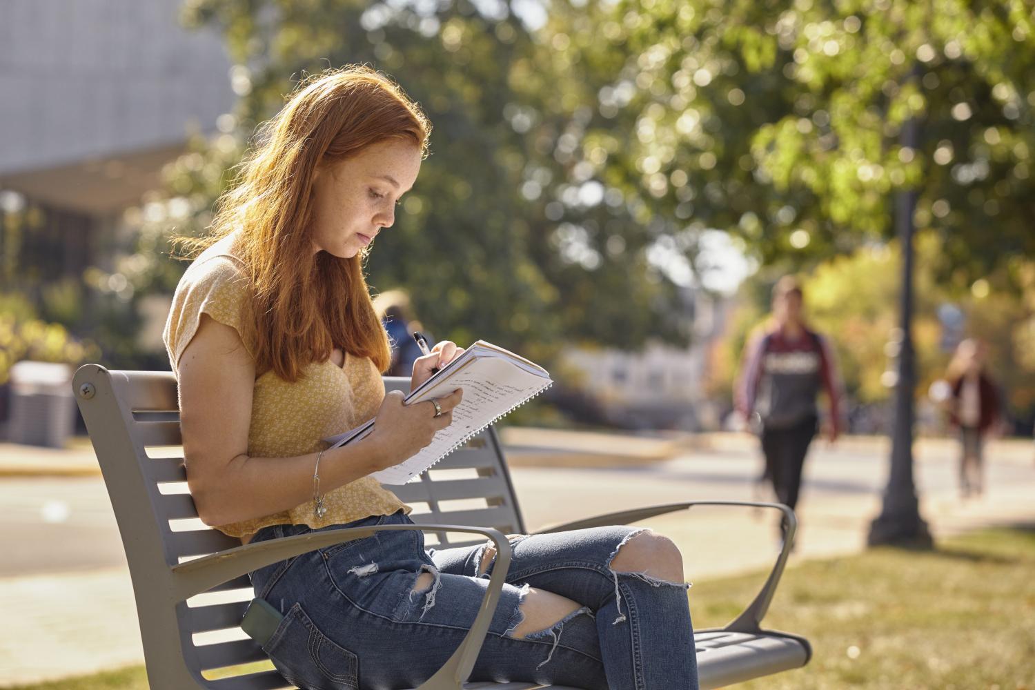 一位<a href='http://r0.tideofdreams.com'>bv伟德ios下载</a>学院的学生在校园里的长椅上读书.